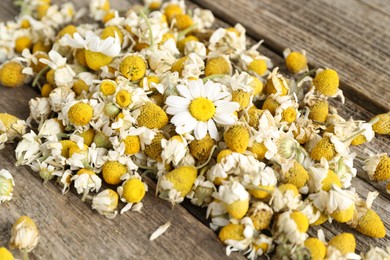 Photo of Dry and fresh chamomile flowers on wooden table, closeup