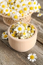 Dry and fresh chamomile flowers on wooden table