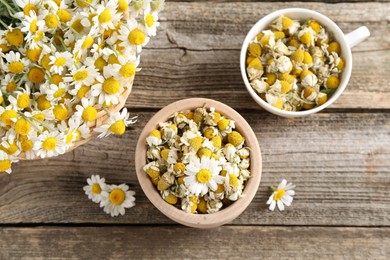 Photo of Dry and fresh chamomile flowers on wooden table, flat lay