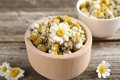 Photo of Dry and fresh chamomile flowers on wooden table, closeup