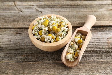 Chamomile flowers in bowl and scoop on wooden table