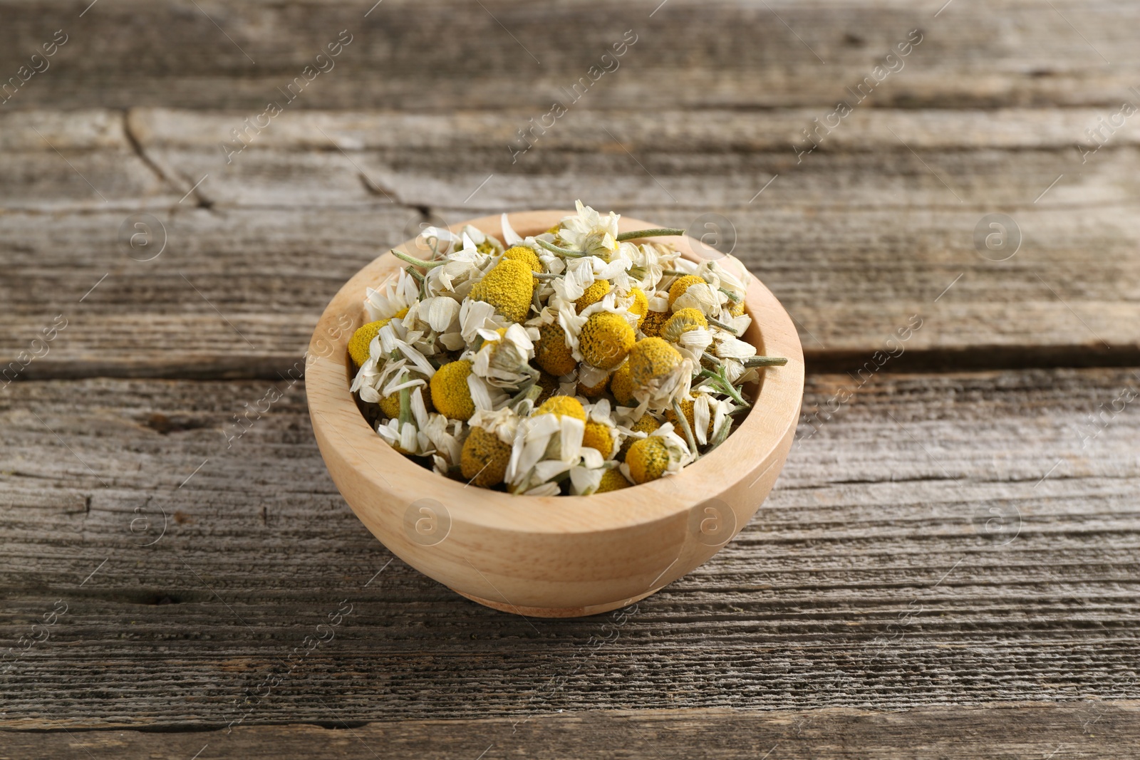 Photo of Chamomile flowers in bowl on wooden table