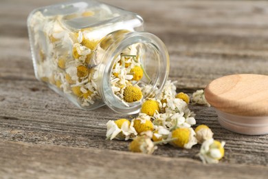 Photo of Chamomile flowers in glass jar on wooden table, closeup