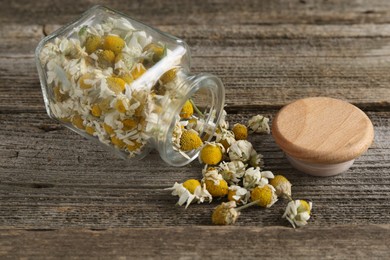 Chamomile flowers in glass jar on wooden table