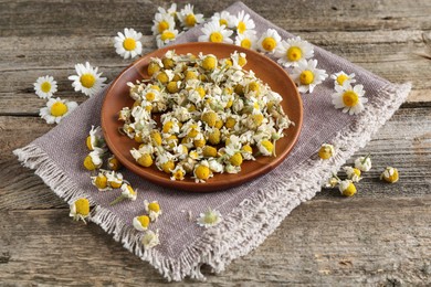 Photo of Dry and fresh chamomile flowers on wooden table