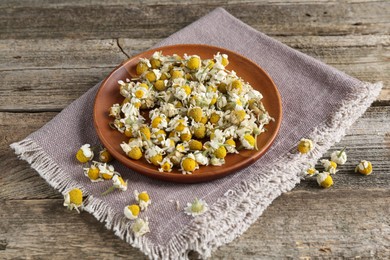 Photo of Chamomile flowers and napkin on wooden table