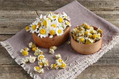 Photo of Dry and fresh chamomile flowers on wooden table