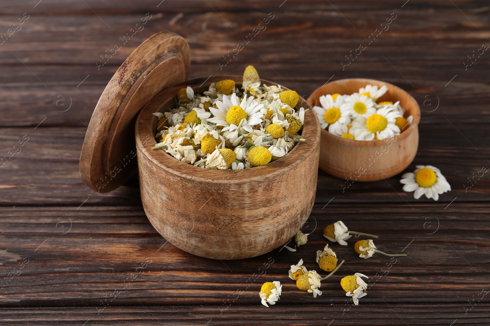 Photo of Chamomile flowers in bowls on wooden table