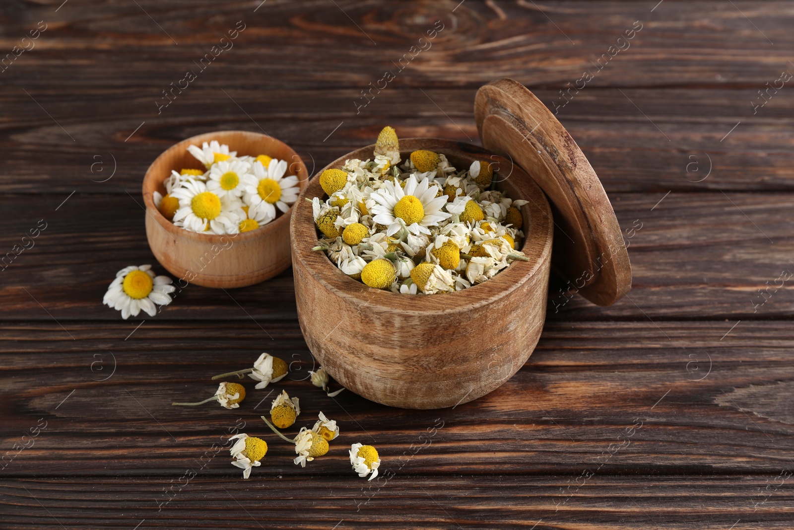 Photo of Chamomile flowers in bowls on wooden table