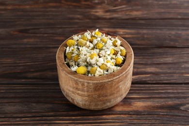 Photo of Chamomile flowers in bowl on wooden table