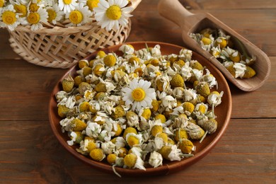 Photo of Dry and fresh chamomile flowers on wooden table, closeup