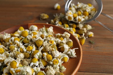 Photo of Many chamomile flowers on wooden table, closeup