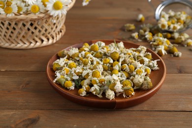 Photo of Dry and fresh chamomile flowers on wooden table