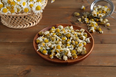 Photo of Dry and fresh chamomile flowers on wooden table