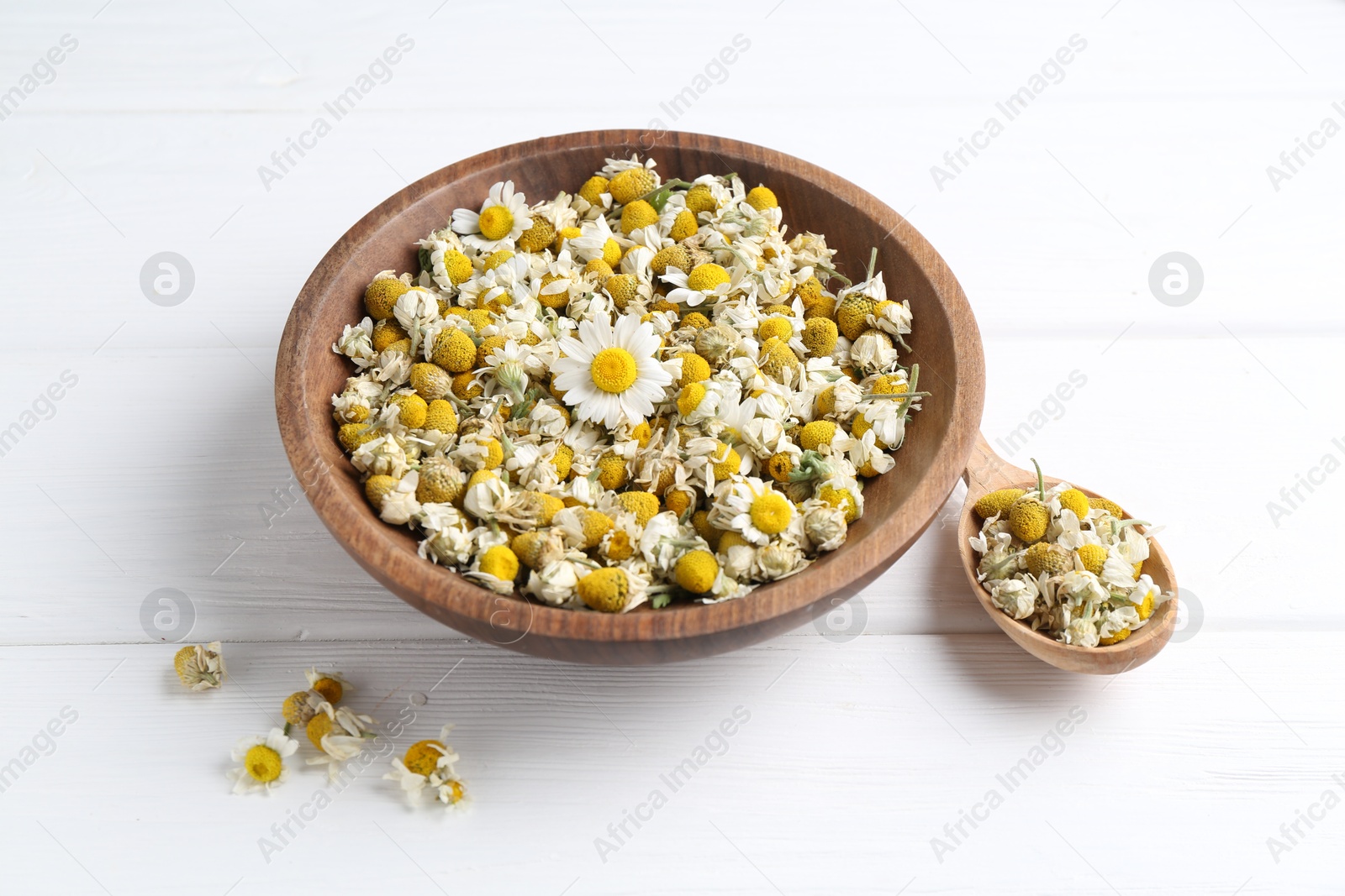 Photo of Dry and fresh chamomile flowers on white wooden table