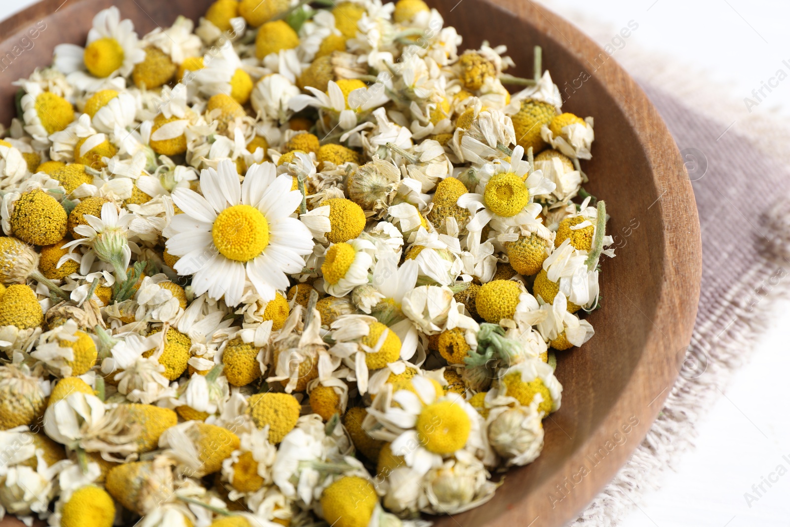 Photo of Dry and fresh chamomile flowers in bowl on white table, closeup