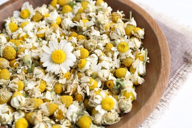 Photo of Dry and fresh chamomile flowers in bowl on white table, closeup