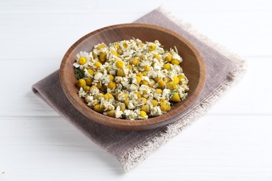 Photo of Dry and fresh chamomile flowers in bowl on white wooden table