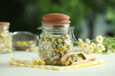 Photo of Dry and fresh chamomile flowers on light table against blurred green background