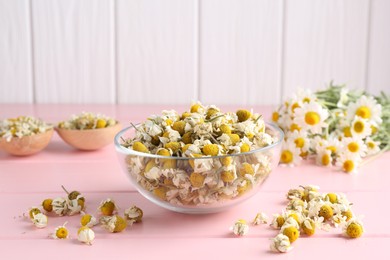 Photo of Chamomile flowers in glass bowl on pink wooden table