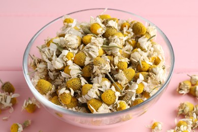 Photo of Chamomile flowers in glass bowl on pink wooden table, closeup