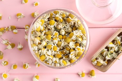 Chamomile flowers in glass jar and scoop on pink wooden table, flat lay