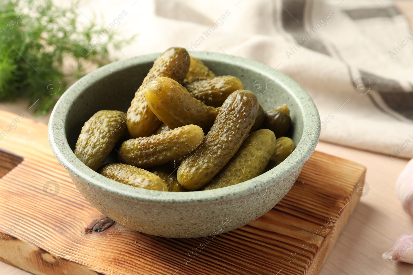 Photo of Pickled cucumbers in bowl on wooden table, closeup