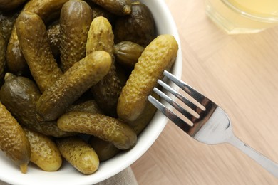 Pickled cucumbers in bowl on wooden table, top view