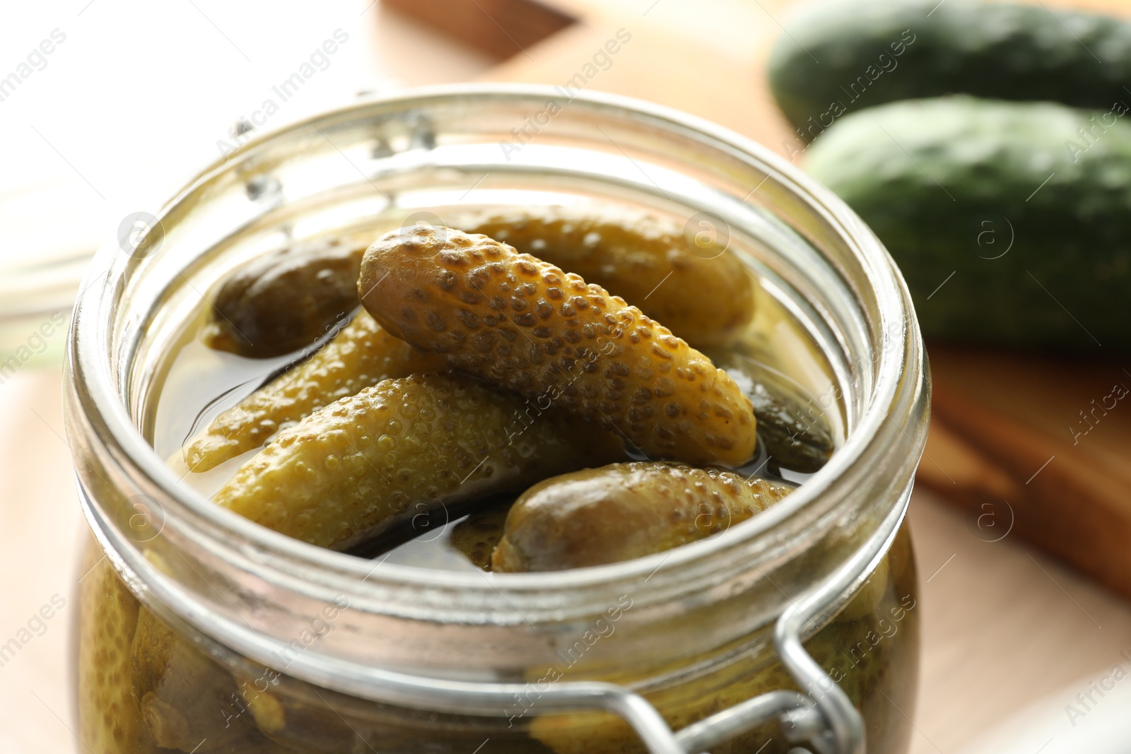 Photo of Pickled cucumbers in open jar on table, closeup