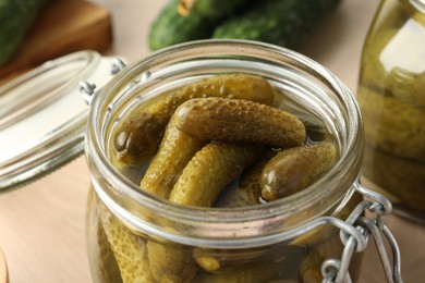 Photo of Pickled cucumbers in open jar on table, closeup