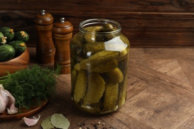 Photo of Pickled cucumbers in jar, vegetables and spices on wooden table. Space for text