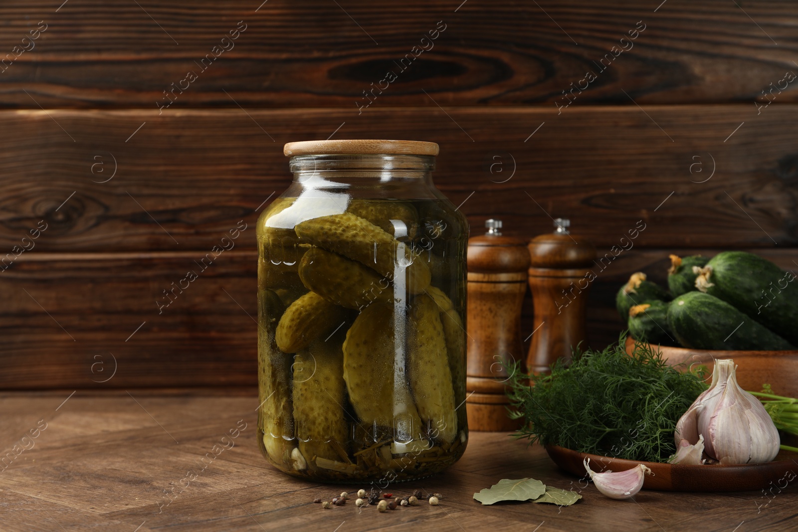 Photo of Pickled cucumbers in jar, vegetables and spices on wooden table. Space for text