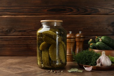 Photo of Pickled cucumbers in jar, vegetables and spices on wooden table. Space for text