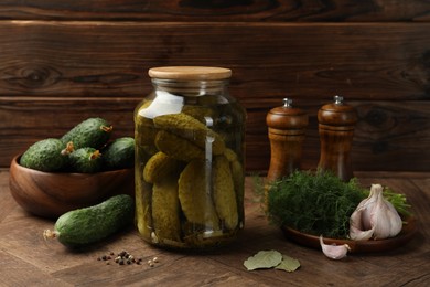 Pickled cucumbers in jar, vegetables and spices on wooden table