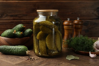 Pickled cucumbers in jar, vegetables and spices on wooden table