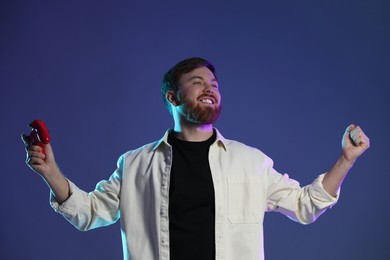 Photo of Happy man with game controller on dark blue background