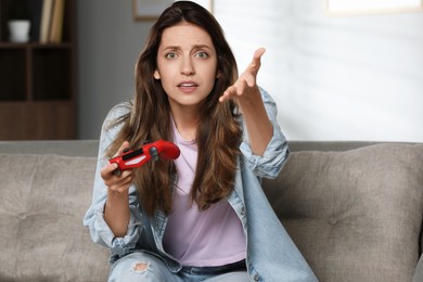 Confused woman with game controller at home