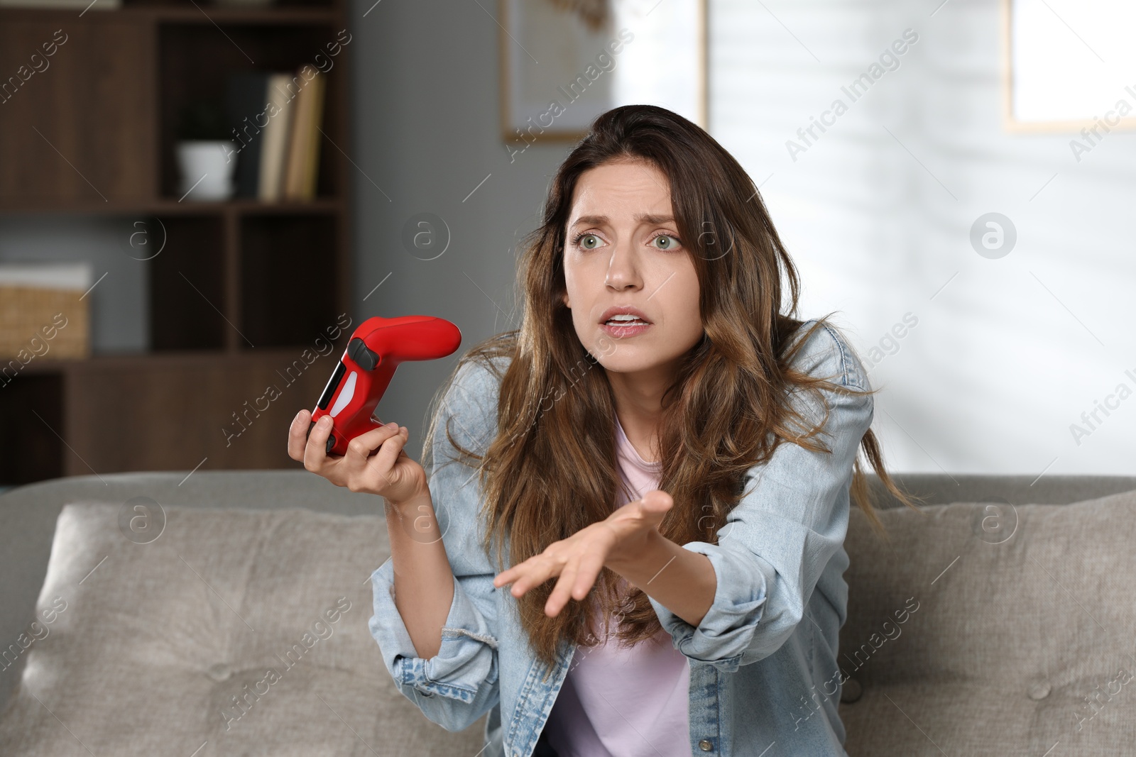 Photo of Confused woman with game controller at home