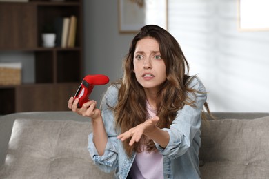 Confused woman with game controller at home