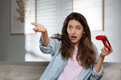 Confused woman with game controller at home