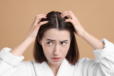 Sad woman with hair loss problem on light brown background