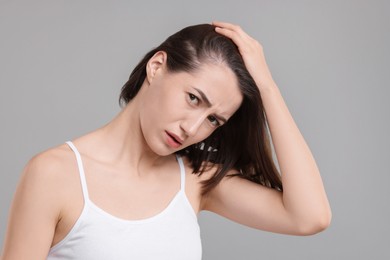 Sad woman with hair loss problem on grey background