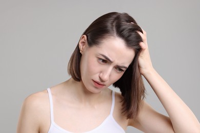 Sad woman with hair loss problem on grey background