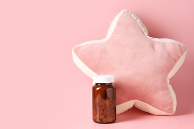 Photo of Star shaped pillow and bottle of pills on pink background, space for text