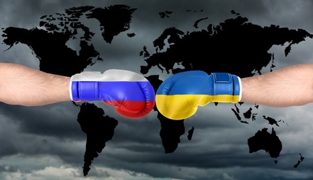 Political conflict, banner design. Men in boxing gloves with flags of Russia and Ukraine fighting against world map, closeup