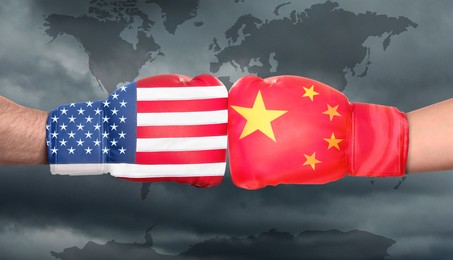 Image of Political conflict, banner design. Men in boxing gloves with flags of USA and China fighting against world map, closeup