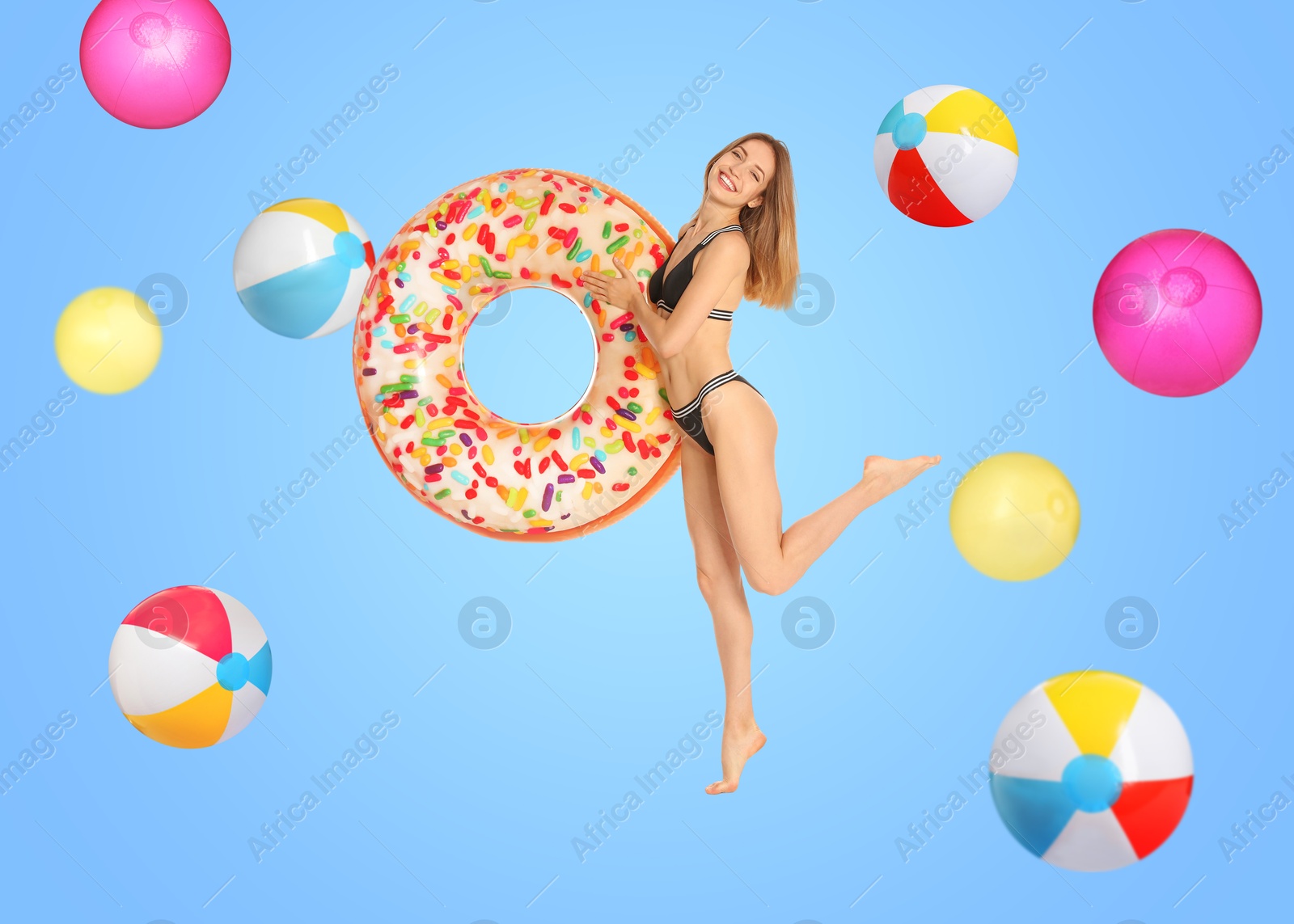 Image of Happy woman with inflatable ring among falling beach balls on light blue background. Summer vibe