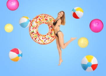 Image of Happy woman with inflatable ring among falling beach balls on light blue background. Summer vibe