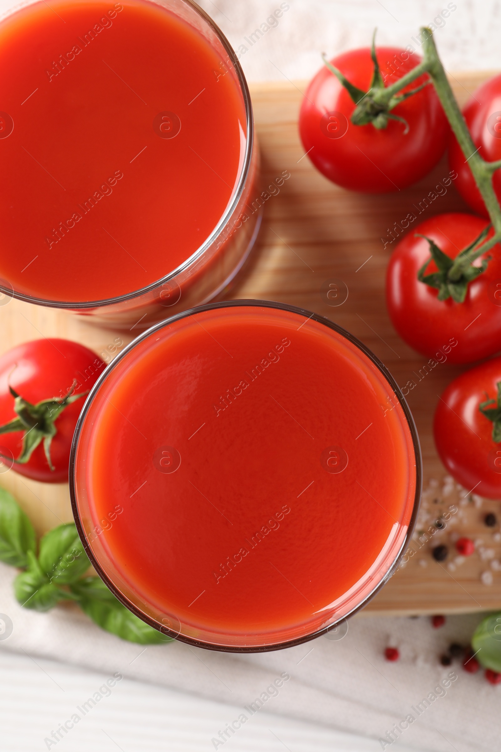 Photo of Tasty tomato juice in glasses with fresh vegetables and spices on white table, flat lay