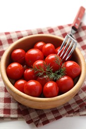 Photo of Tasty pickled tomatoes in bowl, dill and fork on white table